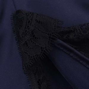 Vue macro du tissu satiné bleu marine avec dentelle florale noire et détails ciselés