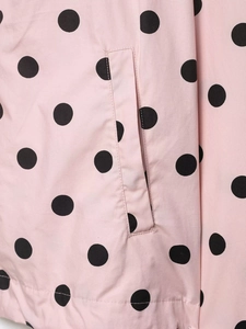 Detail shot of the vertical side pocket on a pink polka dot casual jacket for women