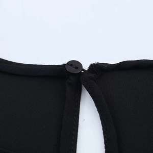 Detail of black dress neckline with round button closure and teardrop back opening