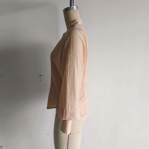 Détail de la texture plissée et des boutons décoratifs sur une chemise beige