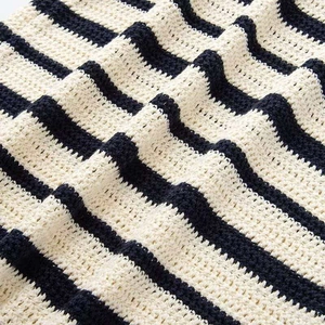 Dettaglio della trama in maglia a righe e motivo all'uncinetto crema e blu navy