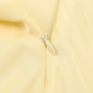 Detail of invisible zipper on light yellow satin midi dress with premium fabric texture