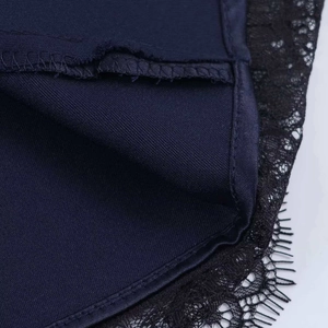 Détail montrant la dentelle noire raffinée sur le tissu d'une robe courte bleu foncé