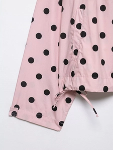 Close-up of pink polka dot jacket detailing drawstring hem and side pocket texture