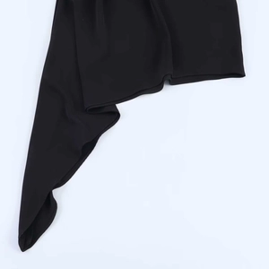Detail shot of the asymmetric hemline and premium fabric of this black mini dress