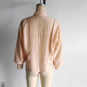 Détail d'une chemise rose avec des plis verticaux texturés et des épaules tombantes