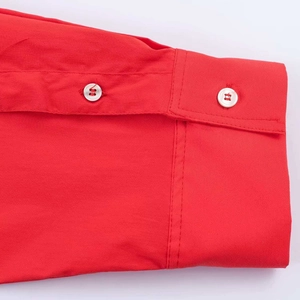 Detailed macro view of the red shirt sleeve with clean white resin buttons and neat stitching