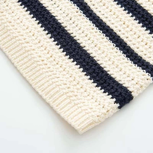Dettaglio dell'abito in maglia a righe beige e blu con trama all'uncinetto e bordo