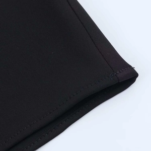 Detail shot of the asymmetrical hemline stitching and black twill fabric texture on a dress