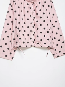 Detailed view of pink polka dot jacket featuring drawstring hood and pearl-like buttons