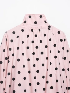 Detail of pink polka dot jacket showing high neck pleats and long sleeve fabric texture