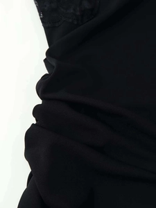 Detail view of delicate black lace patchwork and pleated fabric on summer dress