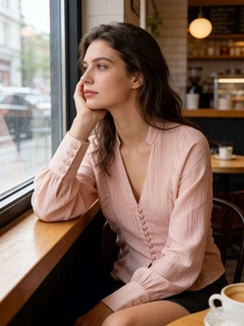 Détail de chemisier rose clair avec col en V et boutons décoratifs sur le devant