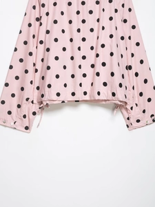 Detail of pink polka dot jacket showing drawstring hem and silver button cuffs