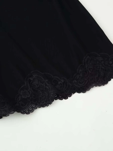 Detailed macro view of delicate black lace hem embroidery on a summer dress