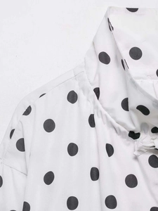 Close-up of stand-up collar and black polka dot pattern on white long sleeve jacket