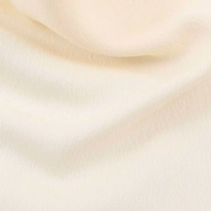 Detailed close-up showing the fine texture and drape of the soft cream textile fabric