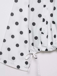 Detailed view of polka dot jacket featuring side slit and drawstring bow hem detail