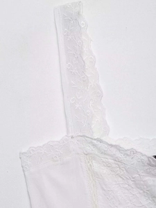 Detailed view of white tank top with eyelash lace trim and floral embroidery accents