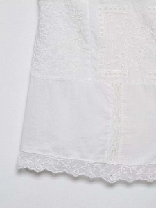 Detail of white lace hem featuring floral embroidery and hollow-out stitching on fabric