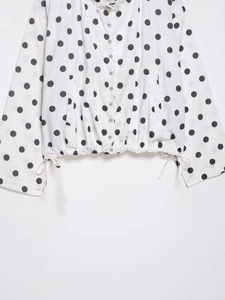 Close-up of black polka dot pattern with drawstring hem and button details on jacket