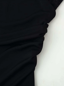 Detail of black summer dress with layered pleats and delicate lace stitching