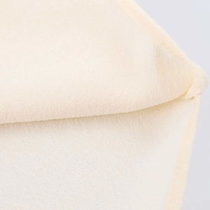 Detailed macro view of cream asymmetric halter top fabric with micro-wrinkle texture