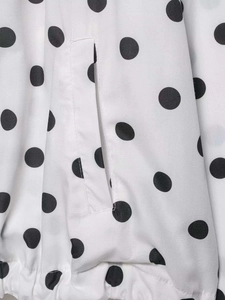 Detail of polka dot jacket showing the welt pocket and elastic hem on woven fabric
