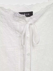 Detailed view of white floral embroidery and lace texture on a summer camisole top