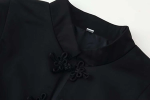 Detailed close-up of a black jacket featuring a mandarin collar and traditional knotted buttons
