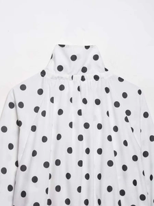 Close-up of the standing collar and pleated detailing on white polka dot chiffon shirt