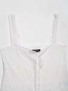 Detail of white lace camisole showing delicate embroidery and bow tie fastener