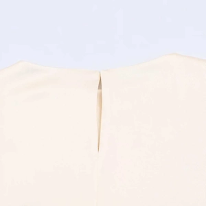 Dettaglio dell'elegante camicetta in raso color crema con raffinato scollo a goccia