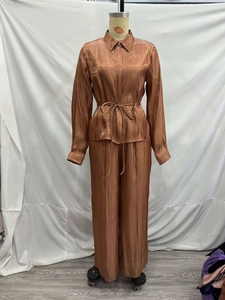 Detailed texture of bronzed satin two-piece set with drawstring shirt and wide-leg trousers