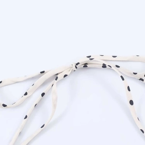Detailed macro view of black polka dot pattern and thin woven tie-up straps on white fabric