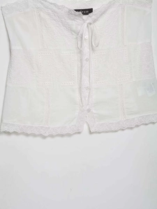 Detail of white vintage lace camisole with embroidery, button closure and tie neck