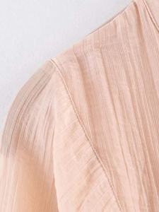 Détail du tissu plissé rose montrant les coutures précises sur les coutures des épaules