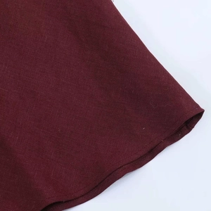 Detailed close-up of wine red linen fabric texture and hem stitching on midi dress