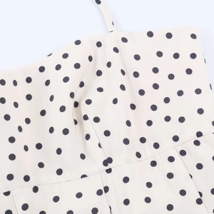 Detail of white midi dress with black polka dots featuring thin straps and fine stitching
