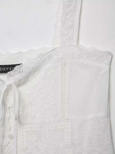 Detailed view of white lace camisole with floral embroidery and scalloped edges
