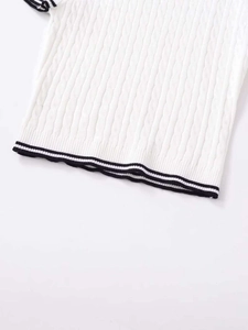 Detail of cable-knit texture and black-white striped hem on white short sleeve sweater