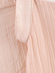Vue macro détaillée de la texture du tissu plissé et de l'encolure d'un chemisier rose