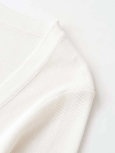 Detail of flat shoulder seams and V-neckline texture on white knitted long sleeve top