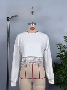 Close-up of women's white cropped sweatshirt with delicate lace hem and ribbed cuffs