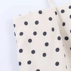 Macro shot of beige halter midi dress fabric showing detailed black polka dot patterns