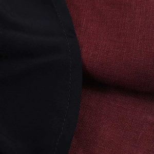 Detail of fabric stitching on a black jersey and burgundy textured linen midi dress