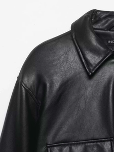 Gros plan d'une veste en cuir noir avec col à revers classique et texture grainée fine