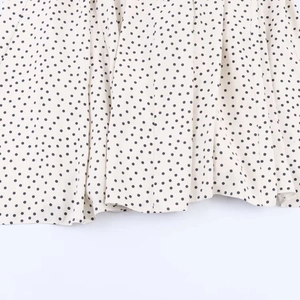 Detail shot of ivory midi dress showing polka dot pattern and lightweight chiffon fabric