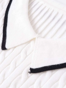 Close-up of cable knit texture and contrasting black trim on a white polo neck knit top