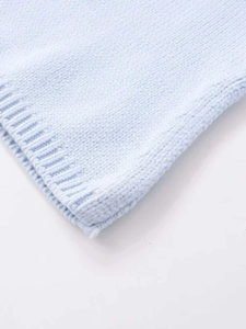 Close-up of light blue knit vest showing fine stitch texture and ribbed edge detailing